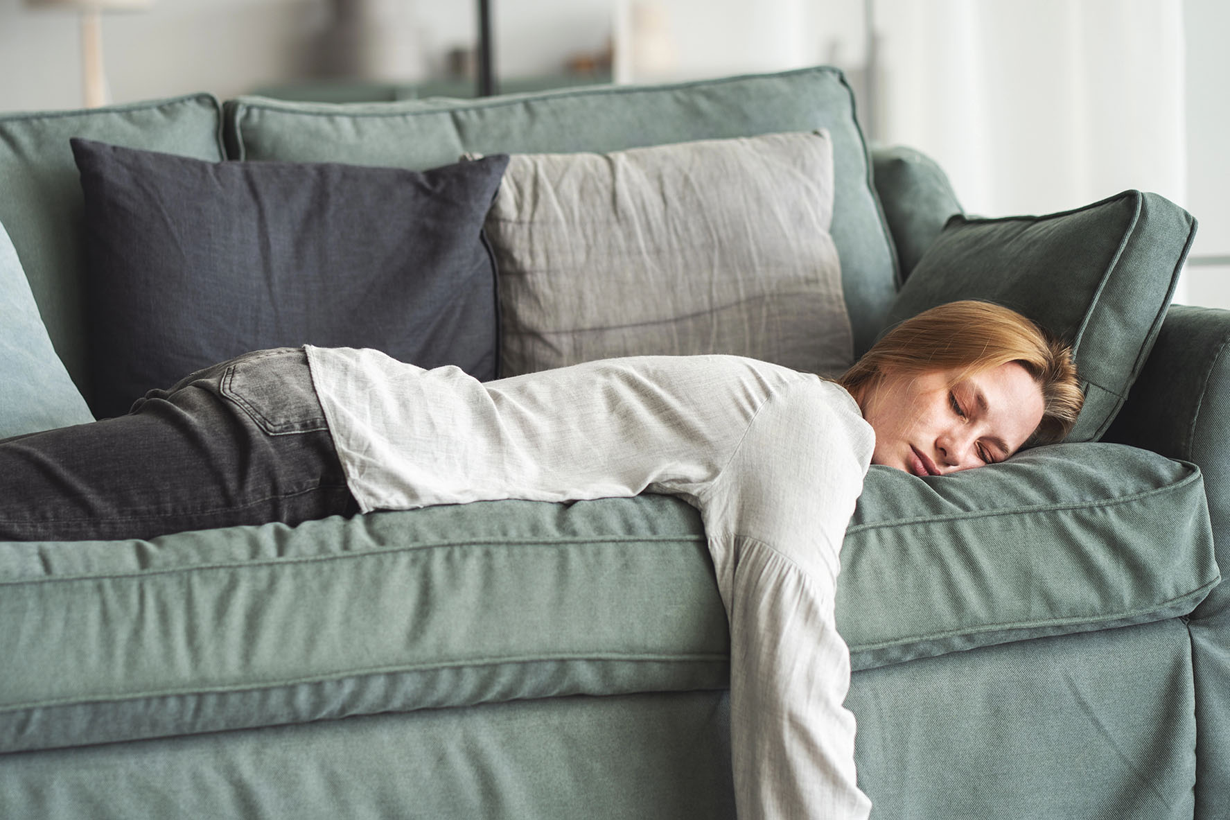 Erschöpfte Frau liegt bäuchlings auf dem Sofa.